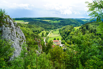 Fototapeta na wymiar Scenic view of a green valley and forested hills near the village of Gundelfingen, Germany. This countryside is famous for fresh green nature and rough, forested hills.