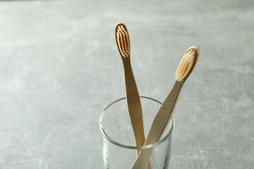 Glass with eco friendly toothbrushes on gray background