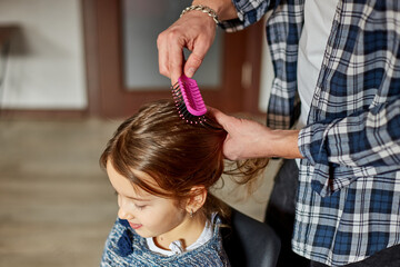 Fototapeta premium Father combing, brushing his daughter's hair at home
