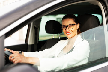 Beautiful businesswoman driving a car. Portrait of smiling woman sitting in the car.