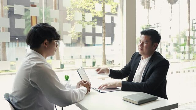 Male manager is talking or explaining about having to dismiss the employee while being handed out a resignation envelope to the employee.