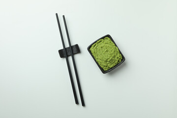 Chopsticks and wasabi sauce on white background