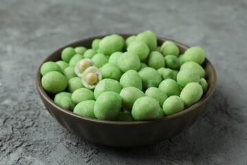 Bowl of wasabi nuts on gray textured background