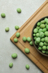 Board with bowl of wasabi nuts on white textured background