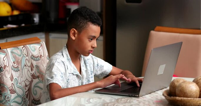 Hispanic boy typing on laptop. South american child using computer for study