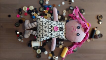 Fototapeta na wymiar Rag doll, emotional, PATCH - LALLI frowns. An emotional doll made of leftovers. He's got buttons instead of eyes. Soft, soft and very special. ON ONE SIDE HE SMILES FROM THE OTHER FROFROWNING.