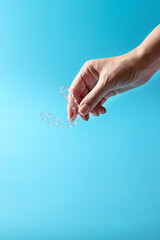 Hand holding Invisalign, the invisible braces aligner, orthodontic apparatus for the correction of teeth. Dental concept.