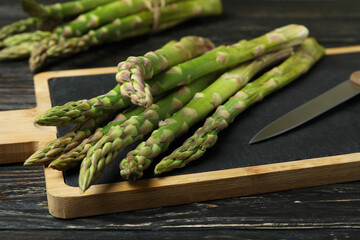 Cutting board with green asparagus on wooden background