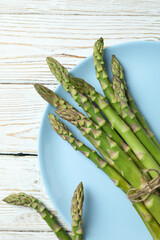 Plate with green asparagus on wooden background