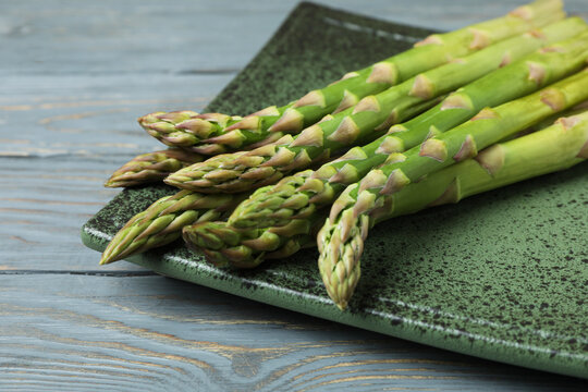 Plate with green asparagus on wooden background