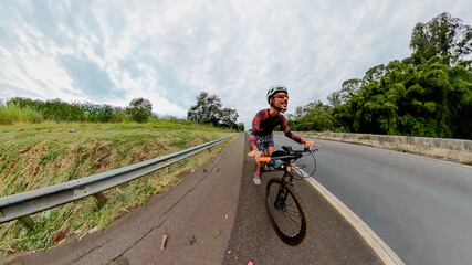 Naklejka premium Black man with helmet and glasses riding a bicycle on the road. Space for text.