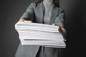Woman a secretary is showing a heap of documents in her hands.