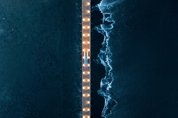 Aerial view of vehicle driving on illuminated bridge over the frozen lake in Trakai, Lithuania.