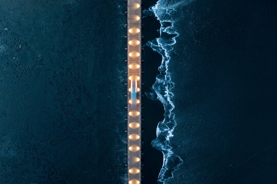 Aerial view of vehicle driving on illuminated bridge over the frozen lake in Trakai, Lithuania.