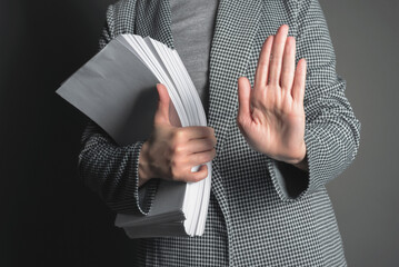 Office worker is showing a stop gesture sign by her hand on the gray background.