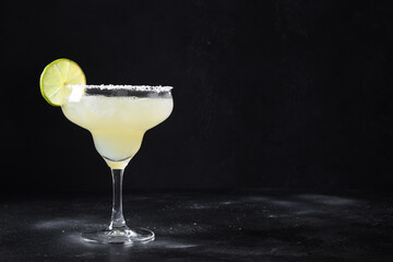 Classic Margarita or Daiquiry cocktail with lime and ice isolated on dark black background with...