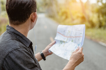 Male traveler holding map for searching route in forest