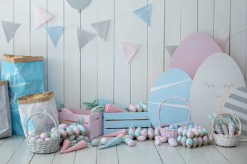Baskets with lot colorful Easter eggs and carrots! Spring home decoration and easter decor. Holiday flags on wooden white wall. Children's room in the Easter style. Colorful Easter room interior.	
