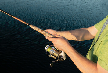 man is fishing on river. Fishing rod in men's hands above the water. Hobby and leisure concept.