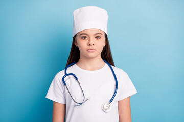 Photo portrait of little girl serious in medical uniform headwear isolated on bright blue color background