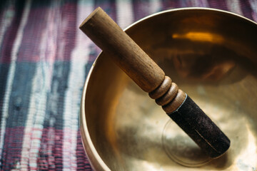 Tibetan singing bowl with a stick on a handmade woven carpet.