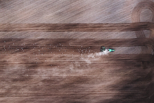 Aerial top down view of tractor harrowing agricultural soil land in countryside, Kaunas, Lithuania.