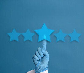 a hand in a blue medical glove presses on a star in the middle of a row on a blue background....