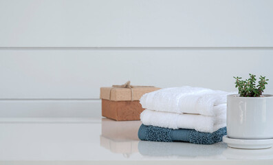 Clean spa towels on white wooden table in bathroom with copy space.