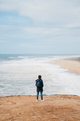 A lonely woman overlooking a beach in Nazare, Portugal