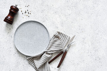 Reserving the table. Empty plate with cutlery and spices on a stone background. View from above.
