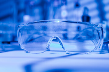 Protective glasses of scientist researcher on a laboratory table, with blue light environment