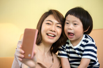 Asian mother and son are taking a selfie photo from a smartphone.