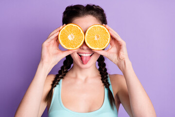 Photo of funky funny young woman cover eyes slice orange stick out tongue isolated on violet color background