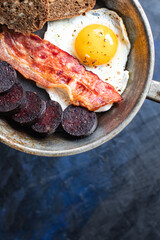 english breakfast fried egg black pudding blood sausage, cereal bread, beans, bacon, scrambled eggs, wholesome food healthy meal snack copy space food background rustic top view
