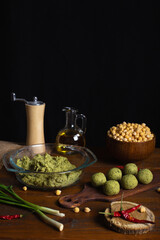 Raw jewish falafel in rustic kitchen on wooden board with copy space. Healthy vegan food, fitness eating. Falafel indredients. Chickpea in bowl, red chili pepper, green onions, olive oil. Vertical
