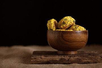 Homemade baked veggie chickpea burgers in brown wooden bowl on black background. Tasty lentils cutlets with greens and spice. Rustic style. Copy space