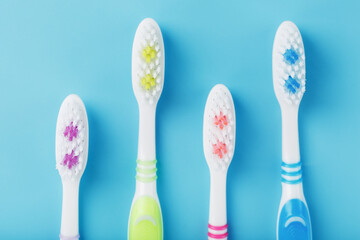 Toothbrushes of different colors in a row on a blue background.