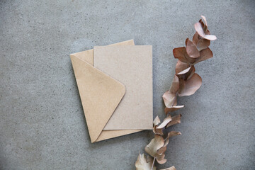 Blank kraft brown invitation stationery card with dried eucalyptus leaves