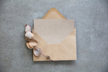 Blank kraft brown invitation stationery card with dried eucalyptus leaves