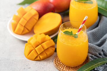 Fresh beautiful delicious mango juice smoothie in a glass cup on gray table background.