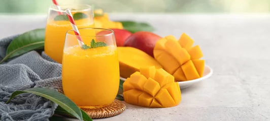 Tuinposter Fresh beautiful delicious mango juice smoothie in a glass cup on gray table background. © RomixImage