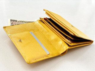 黄色い財布を開いたところに一万円札_斜め