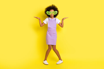 Full size photo of optimistic cute curly girl wear eyewear white t-shirt violet dress sneakers isolated on yellow color background