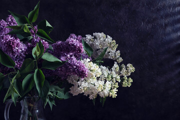 Bouquet of lilacs in jug at night in weak light of moon.