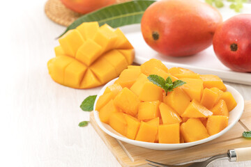Diced fresh mango fruit on a white plate with leaves.