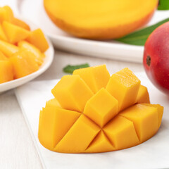 Diced fresh mango fruit on a white plate with leaves.