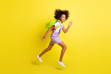 Fototapeta na wymiar Full length body size profile side view of cheerful active wavy-haired girl jumping running isolated over vivid yellow color background