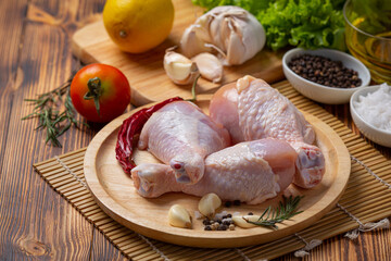 Raw uncooked chicken legs on the dark wooden background.