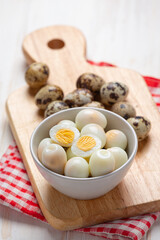 boiled quail eggs on the white wooden background.