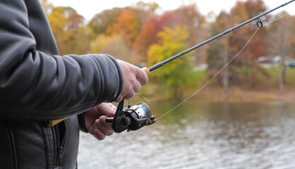 Man holding a fish and rod at the lake during autumn